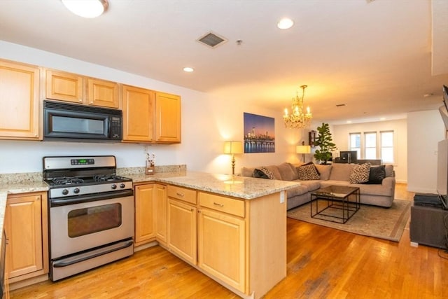 kitchen with gas stove, light stone countertops, kitchen peninsula, a chandelier, and light wood-type flooring