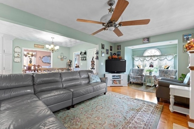 living room featuring ceiling fan with notable chandelier and light hardwood / wood-style floors