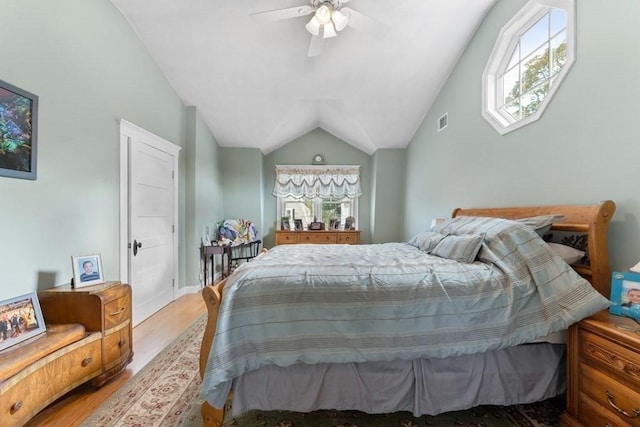 bedroom with ceiling fan, light hardwood / wood-style floors, and vaulted ceiling