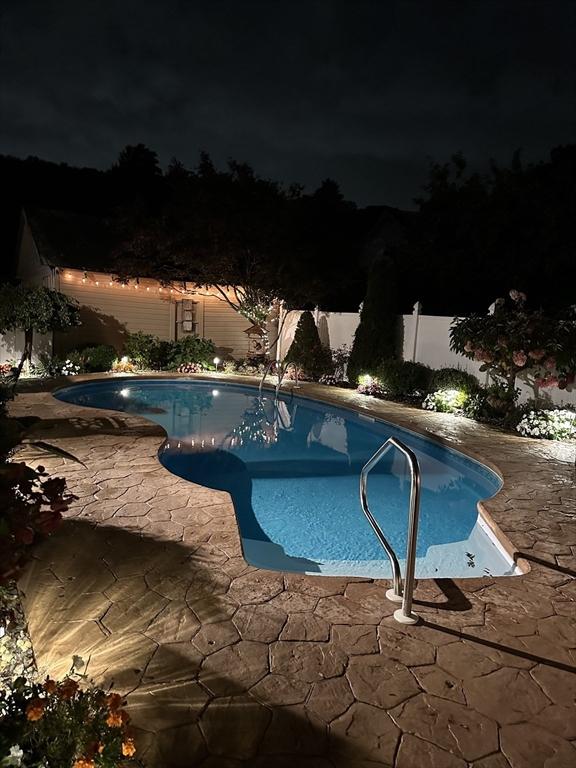 pool at night featuring a patio