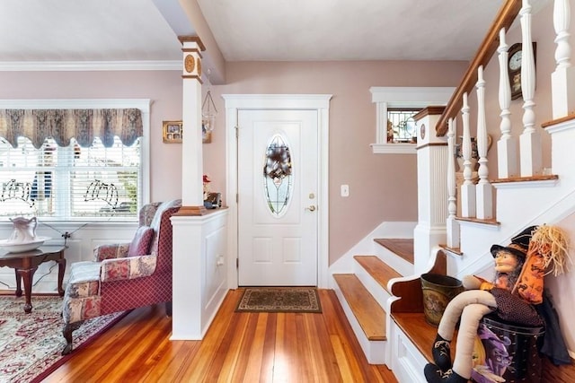 foyer entrance featuring light wood-type flooring, a wealth of natural light, and ornamental molding