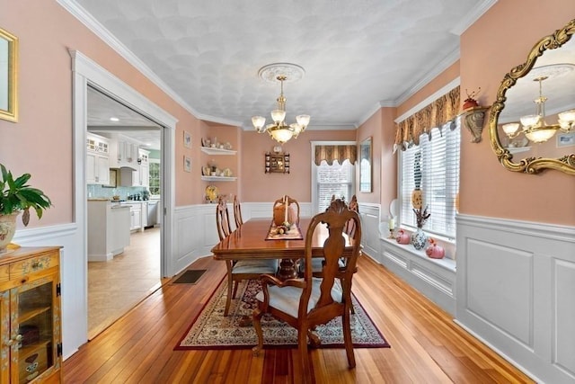 dining space with light hardwood / wood-style flooring, crown molding, and a notable chandelier