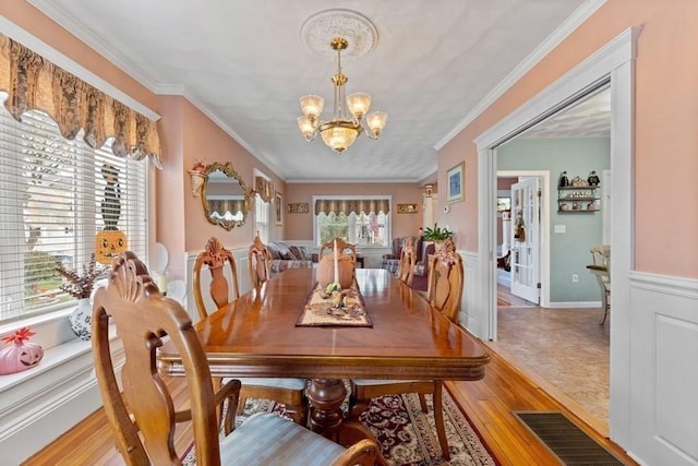 dining space with ornamental molding, a chandelier, and light wood-type flooring