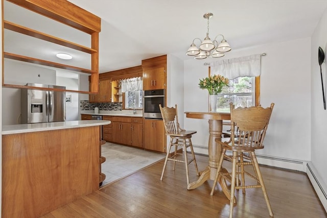 kitchen featuring appliances with stainless steel finishes, open shelves, a chandelier, brown cabinetry, and backsplash