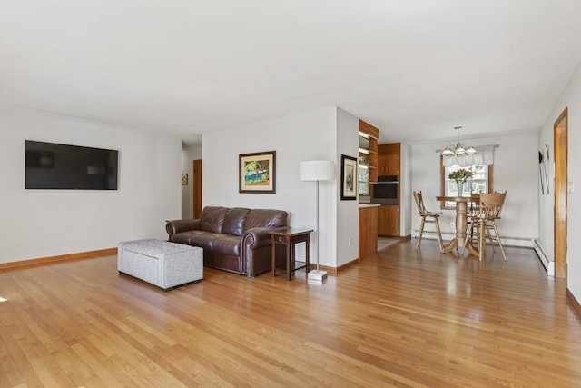 living room with light wood-type flooring, a chandelier, and baseboards