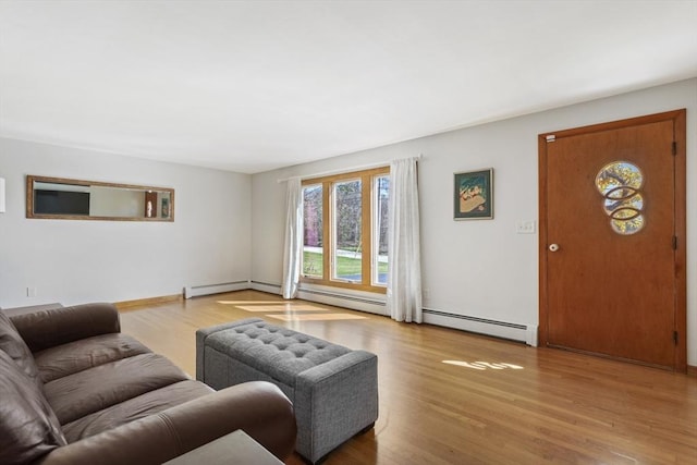 living area with a baseboard heating unit, wood finished floors, baseboard heating, and baseboards