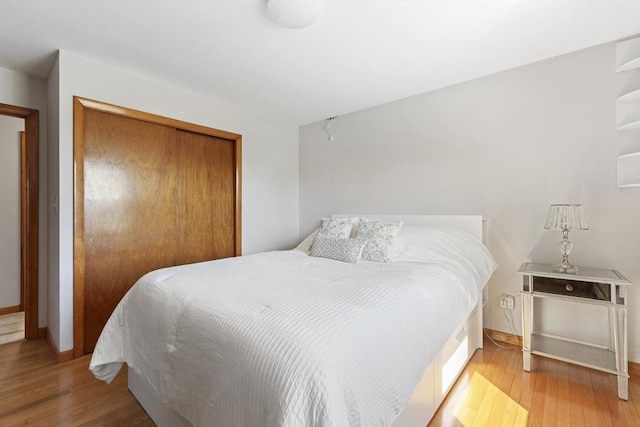 bedroom featuring a closet, wood finished floors, and baseboards