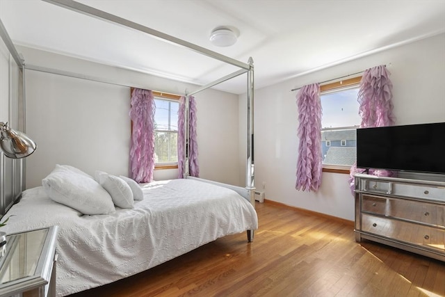 bedroom featuring wood finished floors, a baseboard radiator, and baseboards