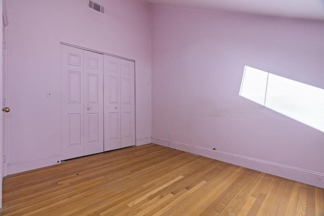 unfurnished bedroom with light wood-type flooring, baseboards, visible vents, and a closet
