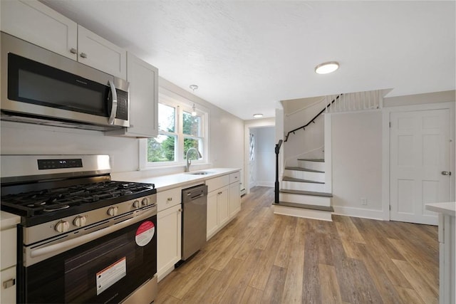 9 Garfield St, Dartmouth, MA 02748 - kitchen featuring appliances with stainless steel finishes, a sink, light countertops, light wood-style flooring, and white cabinetry