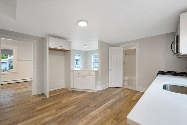9 Garfield St, Dartmouth, MA 02748 - kitchen with a baseboard heating unit, stainless steel microwave, light countertops, light wood finished floors, and white cabinetry