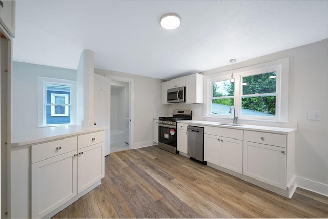 9 Garfield St, Dartmouth, MA 02748 - kitchen with appliances with stainless steel finishes, a sink, baseboards, light wood-style flooring, and white cabinetry