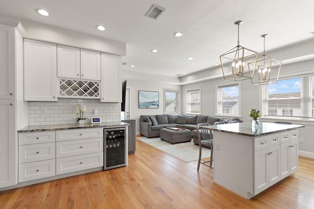 60 Starbird Ave Unit 2, Boston, MA 02131 - kitchen with wine cooler, light wood finished floors, white cabinetry, a chandelier, and recessed lighting