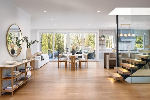 living room with sink, a wall of windows, french doors, and light wood-type flooring