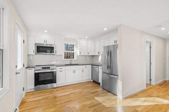 kitchen with white cabinets, decorative backsplash, stainless steel appliances, and sink