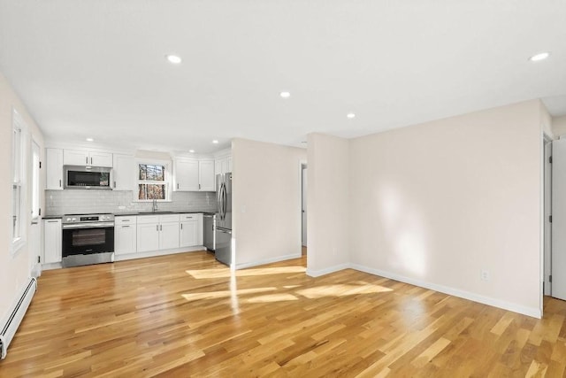 kitchen with white cabinets, sink, tasteful backsplash, stainless steel appliances, and a baseboard radiator