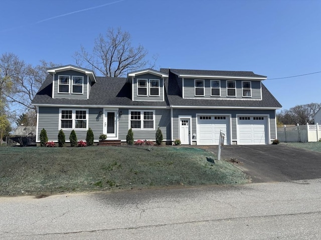 view of front of house with a front lawn, fence, a shingled roof, an attached garage, and driveway