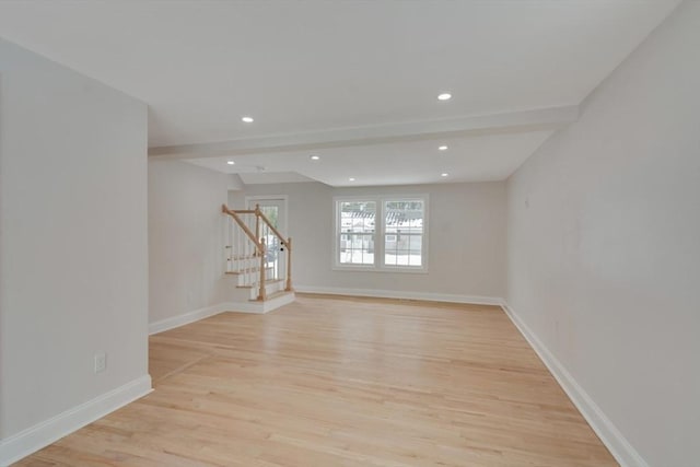 empty room featuring light wood-type flooring, beam ceiling, stairway, baseboards, and recessed lighting