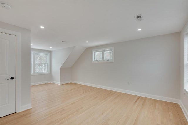 additional living space with baseboards, visible vents, a wealth of natural light, and light wood-type flooring