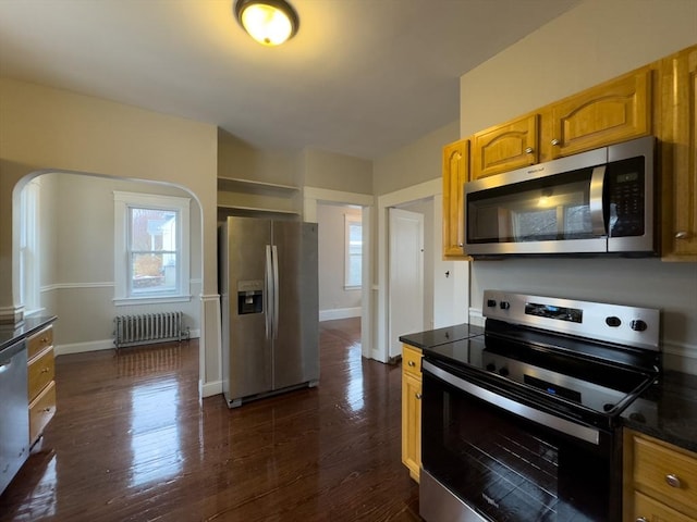 kitchen with appliances with stainless steel finishes, dark hardwood / wood-style floors, and radiator heating unit