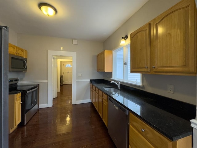 kitchen with dark wood-type flooring, stainless steel appliances, sink, and dark stone counters