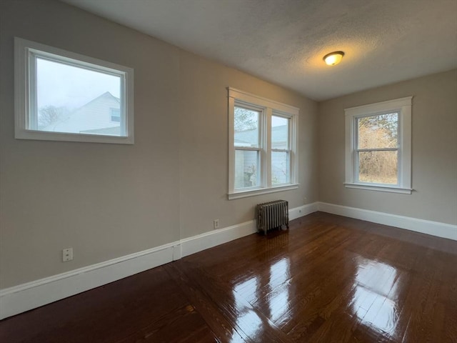 empty room featuring radiator, dark hardwood / wood-style floors, and a textured ceiling