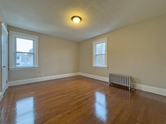 unfurnished room featuring radiator, a wealth of natural light, dark hardwood / wood-style floors, and a textured ceiling