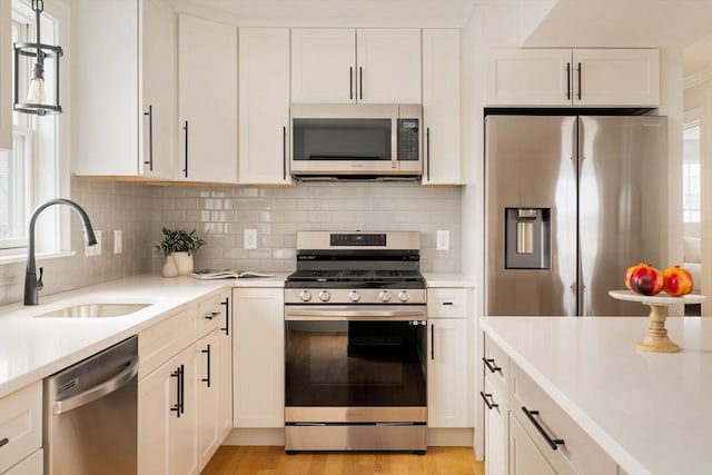 kitchen with decorative backsplash, appliances with stainless steel finishes, light countertops, white cabinetry, and a sink