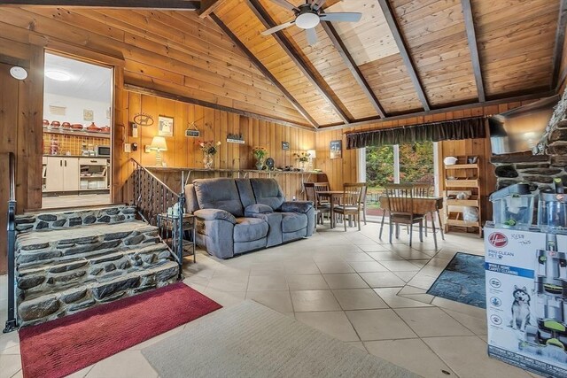 tiled living room with wood ceiling, high vaulted ceiling, wood walls, beam ceiling, and ceiling fan