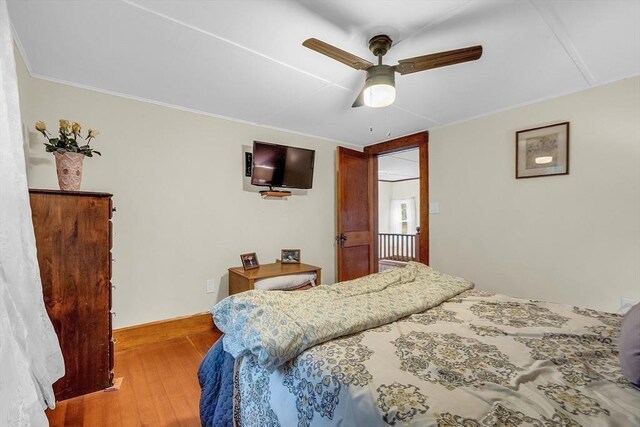 bedroom with wood-type flooring, crown molding, and ceiling fan