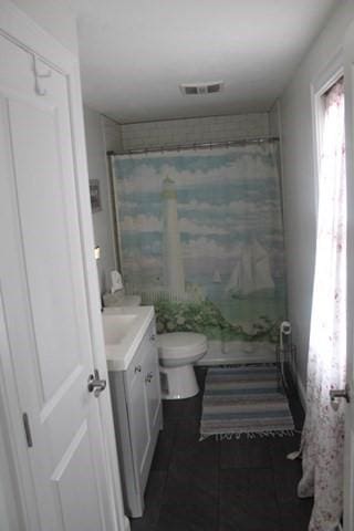 bathroom with toilet, curtained shower, and vanity