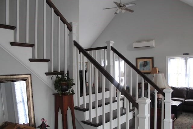 stairway with lofted ceiling, a wall mounted AC, and ceiling fan