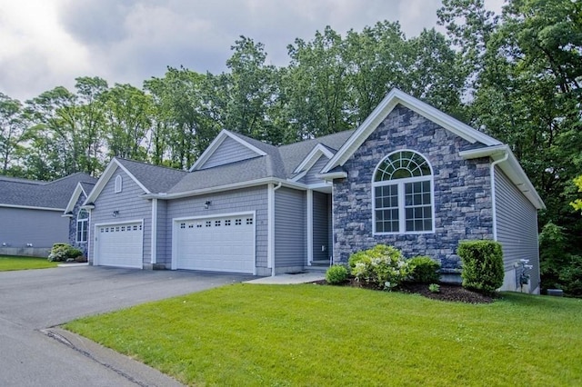 view of front of property featuring a front lawn, stone siding, an attached garage, and aphalt driveway