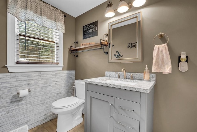 bathroom with vanity, toilet, and tile walls