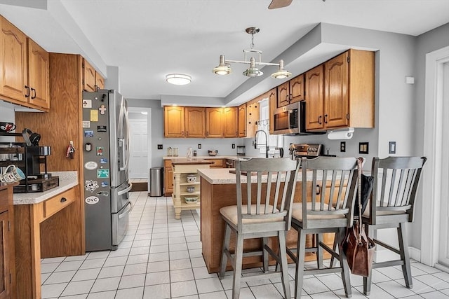 kitchen with stainless steel appliances, kitchen peninsula, decorative light fixtures, a kitchen bar, and light tile patterned floors