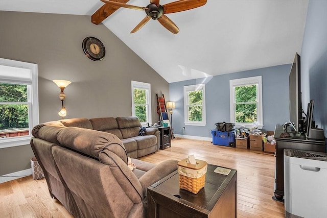 living room featuring beam ceiling, light wood-type flooring, and a healthy amount of sunlight