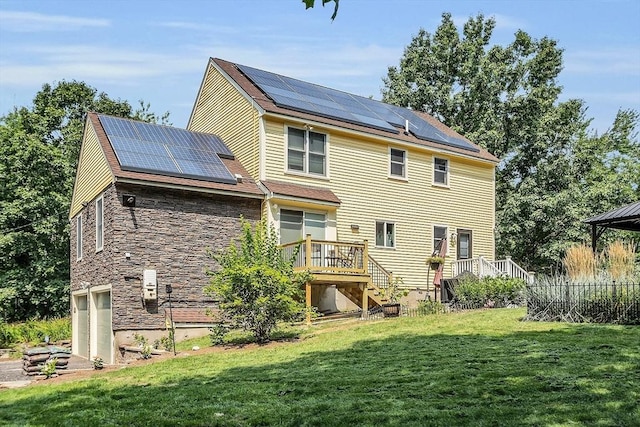 back of house featuring solar panels, a yard, a garage, and a wooden deck