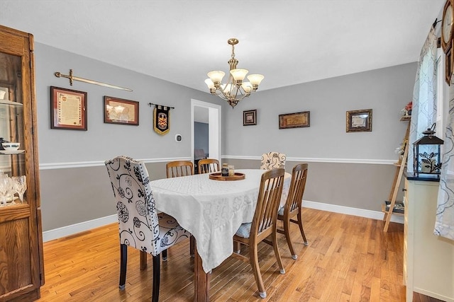 dining space with light hardwood / wood-style flooring and an inviting chandelier