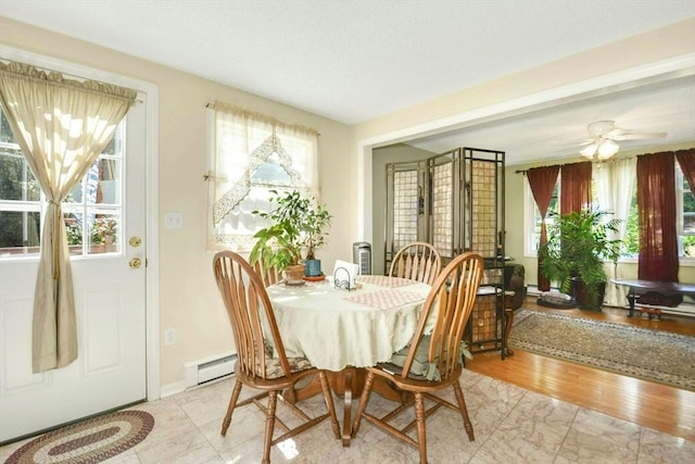 dining room with a baseboard heating unit, ceiling fan, and baseboards