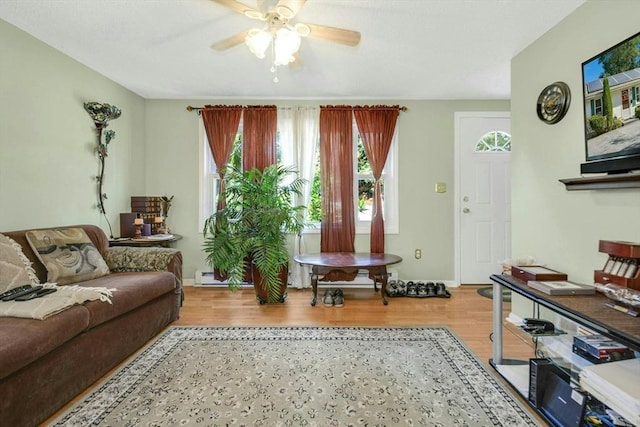 living area with wood finished floors, ceiling fan, and a baseboard heating unit