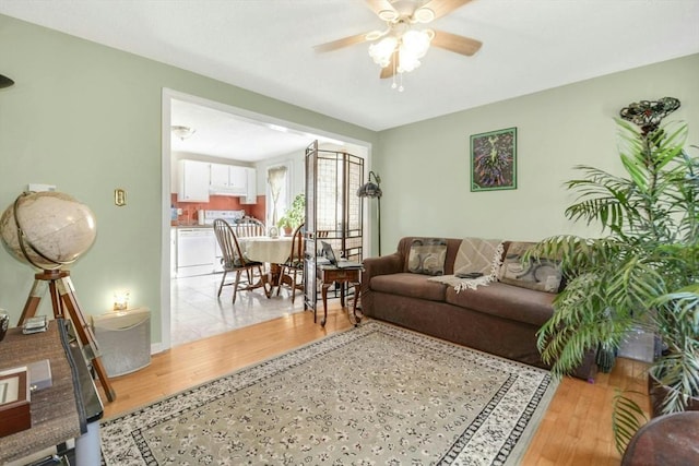 living room with a ceiling fan and light wood-style flooring