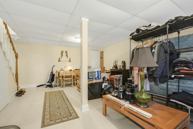 finished basement featuring a paneled ceiling, baseboards, and stairway