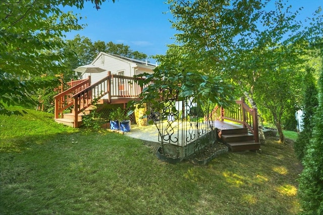view of grassy yard featuring a deck, a patio area, and stairway