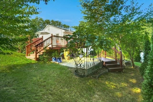 view of grassy yard featuring a wooden deck, a patio area, and stairs