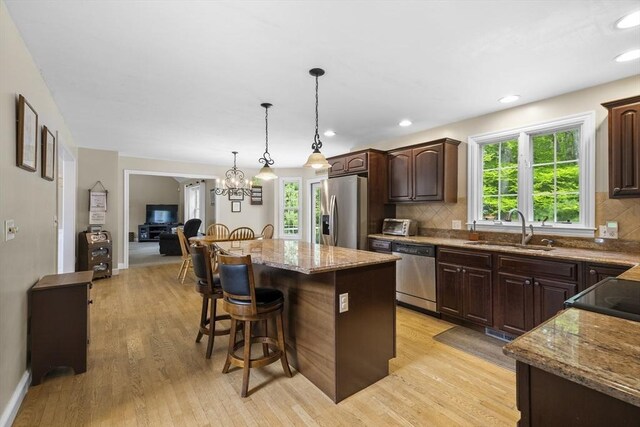 53 Arnold Way, Uxbridge, MA 01569 - kitchen featuring appliances with stainless steel finishes, a kitchen breakfast bar, a kitchen island, light wood-type flooring, and light stone countertops