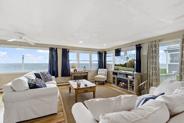 125 Seaview Dr, Plymouth, MA 02360 - living area featuring ceiling fan, a water view, a lit fireplace, wood finished floors, and a baseboard radiator