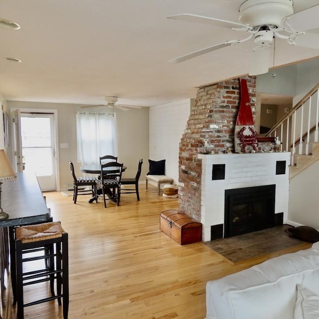 125 Seaview Dr, Plymouth, MA 02360 - living area featuring stairs, a brick fireplace, wood finished floors, and a ceiling fan