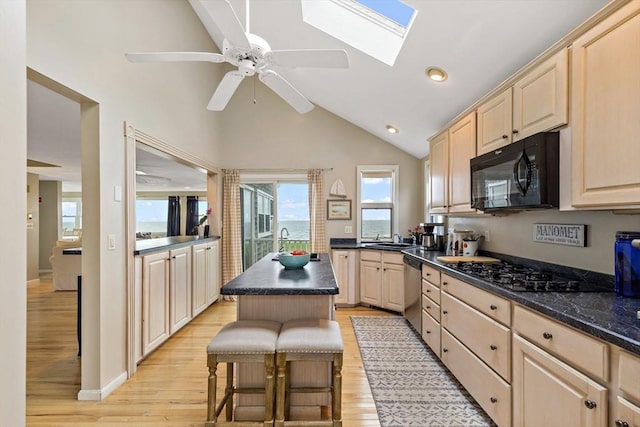 125 Seaview Dr, Plymouth, MA 02360 - kitchen with dark countertops, vaulted ceiling with skylight, light brown cabinets, and black appliances