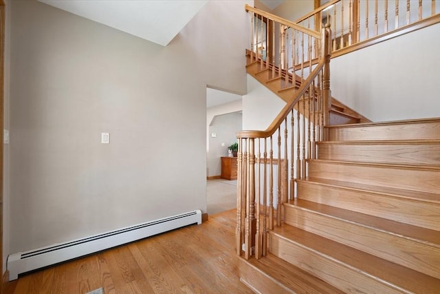 447 Coy Hill Rd, Warren, MA 01083 - staircase featuring a baseboard radiator, wood finished floors, a towering ceiling, and baseboards