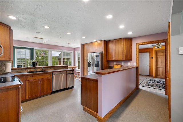 447 Coy Hill Rd, Warren, MA 01083 - kitchen featuring stainless steel appliances, a sink, brown cabinetry, a peninsula, and a textured ceiling